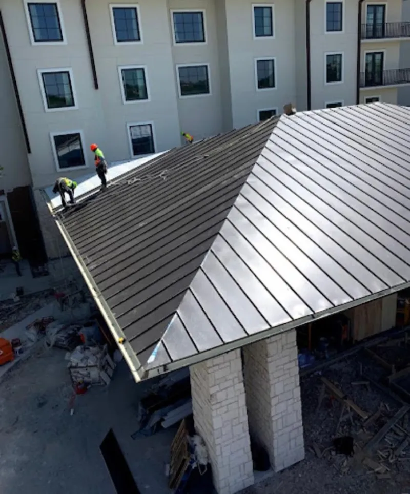 Crew installing standing seam metal roof panels on a commercial project in Gaffney